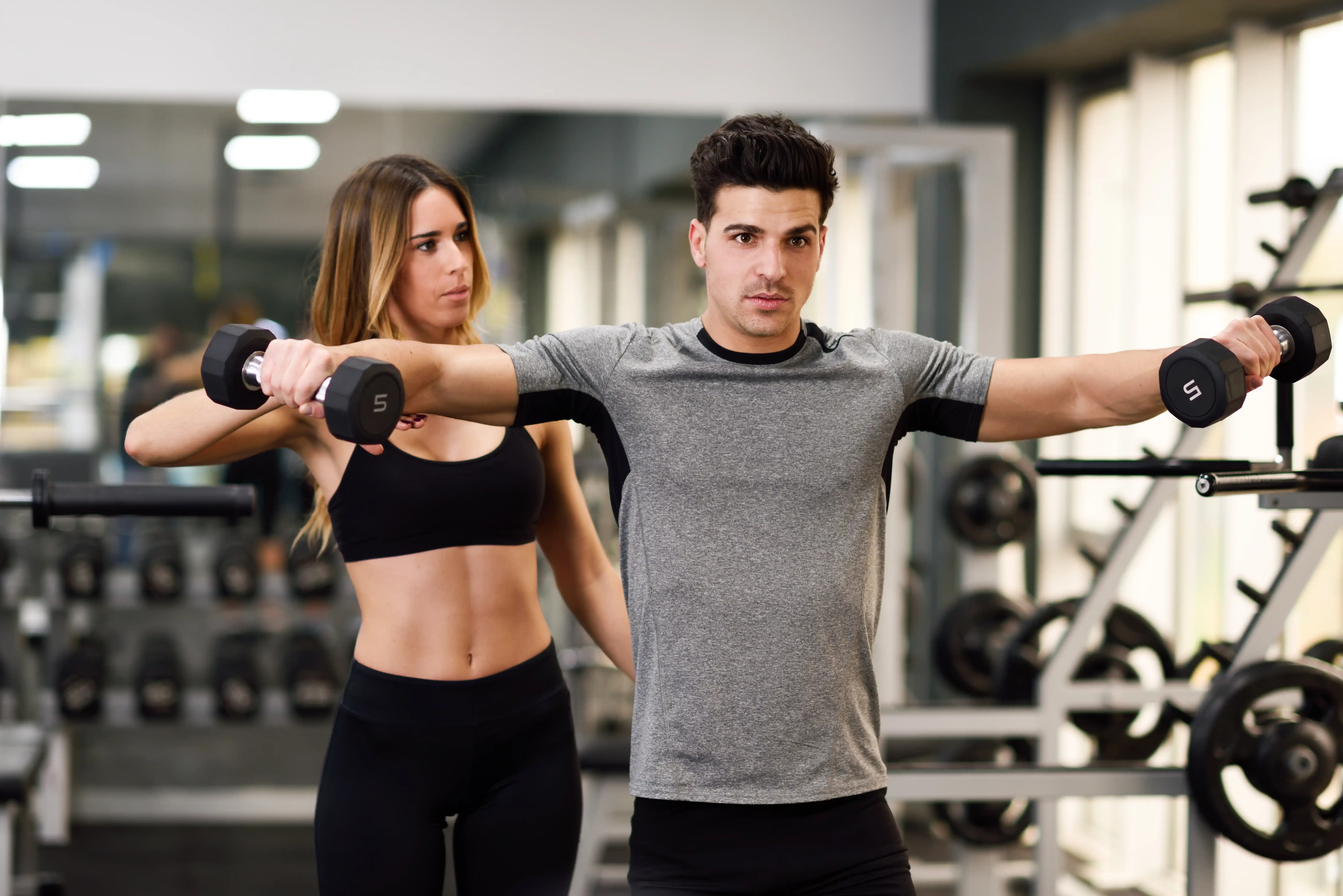 Zeigt einen Mann, der von einem Fitness-Trainer trainiert wird.